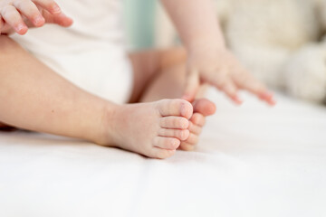 close-up of the legs and arms of a small baby on a light white bed