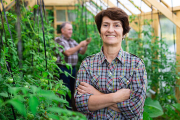 Portrait of happy elderly woman posing in the greenhouse