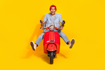 Full length photo of pretty impressed guy dressed denim clothes driving bike isolated yellow color background