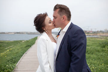A couple in love,  The bride and groom are dressed in a wedding suit and dress, hugging, kissing ech other and posing together
