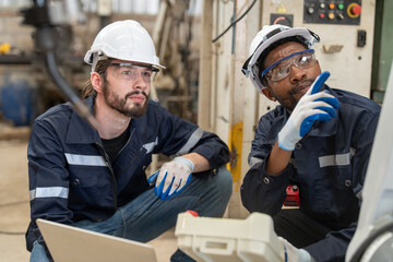 Male engineers wearing vest with helmet safety using laptop and remote controller control...
