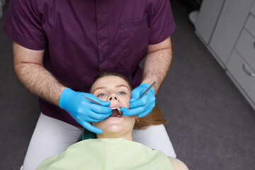 Directly above dentist's hands using dental mirror, examining the oral cavity of a woman patient