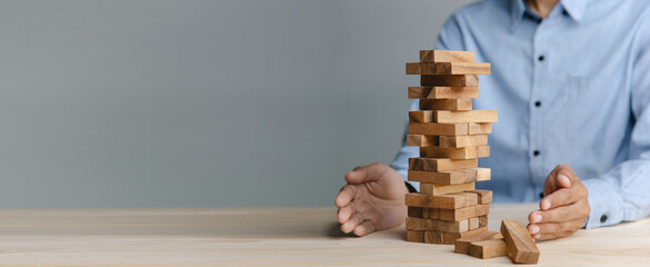 Planning, risk and strategy in business, businessman placing wooden block on a tower.