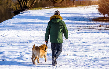 men walk with a dog in a winter park
