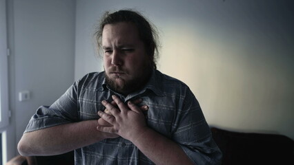 One overweight man having chest pains. A male caucasian person suffering from heart pressure indoors