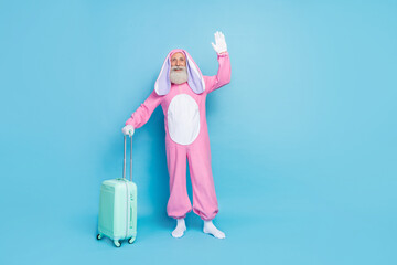 Full length photo of cheerful friendly retired man wear pink hare pajama travelling low-cost flight isolated blue color background