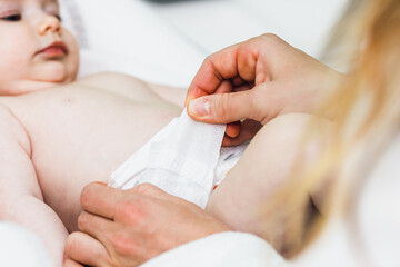 Mother putting diaper on baby in after bathing in bedroom