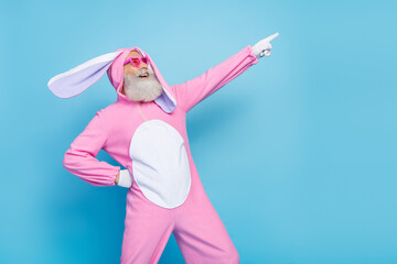 Photo of cool positive retired guy wear pink hare sleepwear heart glasses looking empty space isolated blue color background