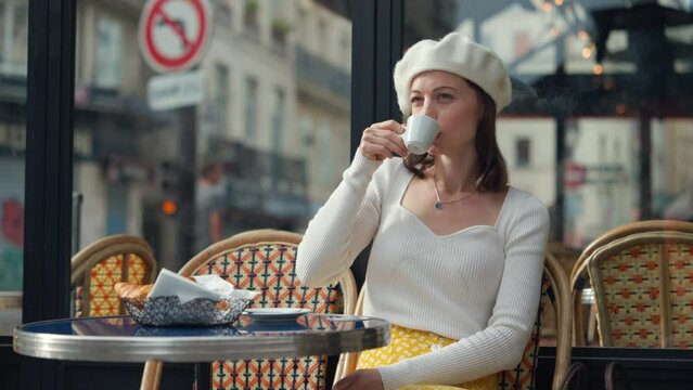 Attractive girl drinking coffee at a table in an outdoor cafe