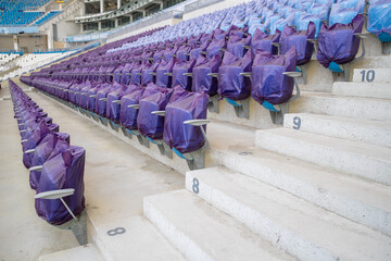 The Olympic Stadium is empty. Empty football stadium - sports events without people. Stadium chair. Numbered steps in a sports stadium between blue plastic seats