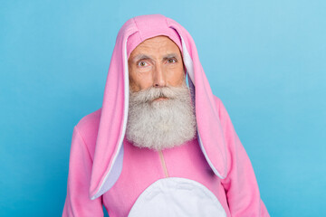 Photo of doubtful unsure retired man wear pink hare pajama suspiciously looking you isolated blue...