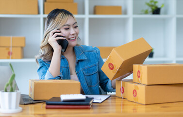 Starting a small business SME owner entrepreneur calling telephone and writing order number receiving and reviewing online orders to prepare to pack boxes, sell to customers, sme business idea online.