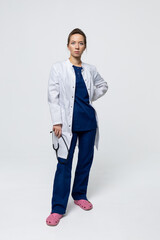 Full-length portrait of a female doctor. A surgeon in a blue suit and a white coat