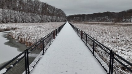 Hiking and walking trail outdoors boardwalk over Genesee River at Turning Point Park, Rochester, NY, during winter with snow 