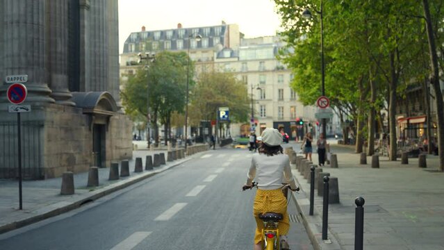 A young girl riding a yellow bicycle through the streets of Paris