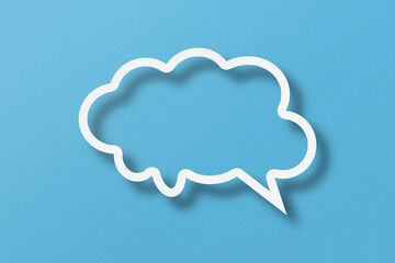White paper cut out speech bubble shapes set on light blue paper background.