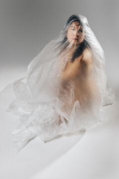 Woman wrapped in polyethylene sitting on floor