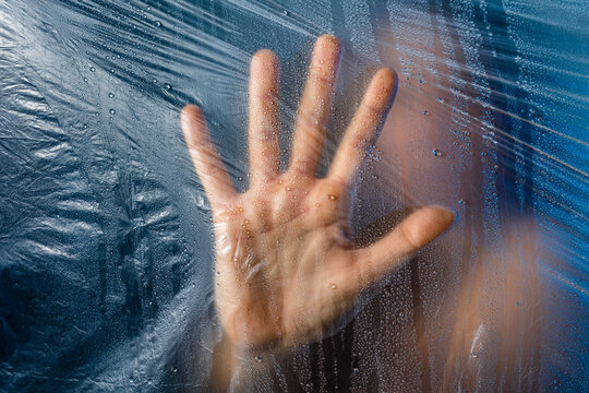 Hand touching plastic film while standing behind it