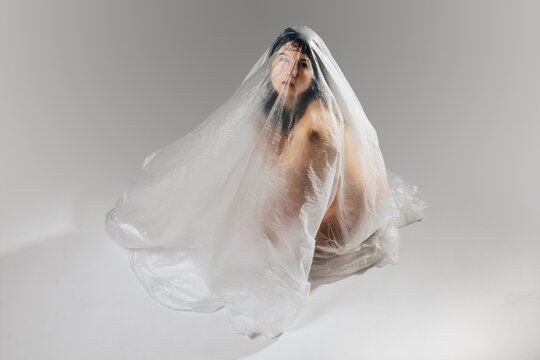 Woman wrapped in polyethylene sitting on floor
