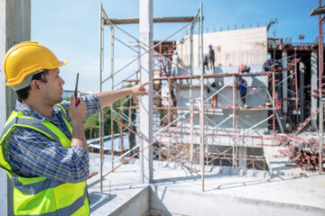 Civil engineer or supervisor inspects and directs workers on a building construction site.