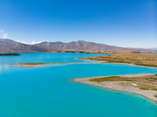 An aerial view of the blue glacial lake - Lake Tekapo, with mountains  and blue sky backgrounds, in South Island, New Zealand