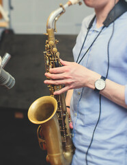 View of a saxophone player in headphones during rehearsal, recording sound for new album song at...