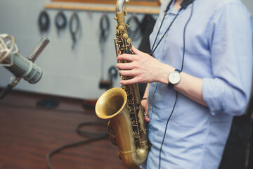 View of a saxophone player in headphones during rehearsal, recording sound for new album song at...