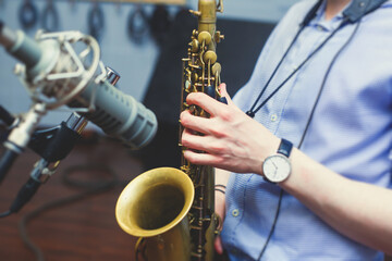 View of a saxophone player in headphones during rehearsal, recording sound for new album song at...
