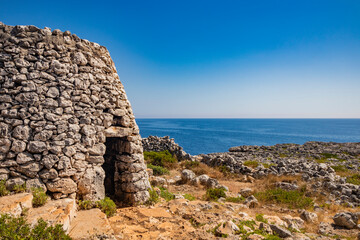 Fototapeta na wymiar Gagliano del Capo. The beautiful panorama on the blue sea, from the rocky cliff of Salento. An old stone trullo. The nature trail that leads from the Ciolo bridge to the spectacular Cipolliane caves.