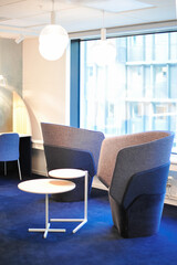 stylish office interior with two plywood coffee tables and comfy armchairs with tall backrest