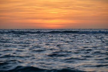 Dramatic red ocean waves at sunset with soft evening sea dark water