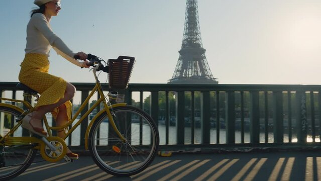 Happy girl riding a yellow bicycle on a bridge overlooking the Eiffel Tower