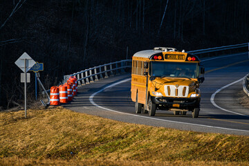 Vehicles drive by a damaged section of guardrail along Rt 79 in Windsor in Upstate NY.  Barrels are placed along the road where an accident recently damaged the guardrail.  Bus at dangerous Curve. - obrazy, fototapety, plakaty