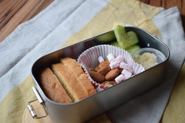 Healthy school lunch box with almonds, bread, vegetables and sweets