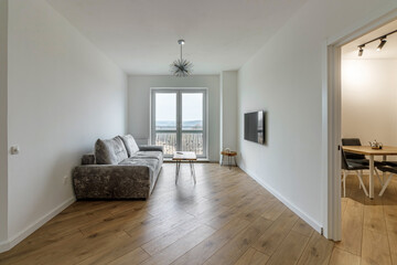 Obraz premium Living room with a gray sofa and a round coffee table and a huge window