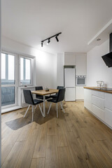 Modern interior of kitchen, wooden furnitureand stylish table and chairs. Spacious and luxurious space in apartment.