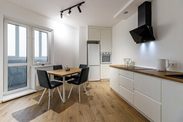 Modern interior of kitchen, wooden furnitureand stylish table and chairs. Spacious and luxurious space in apartment.