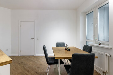 Modern interior of kitchen, wooden furnitureand stylish table and chairs. Spacious and luxurious space in apartment.