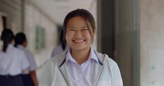 Slow motion scene of a happy smiling and laughing Asian high school student girl who is always have a fun sense of humor.