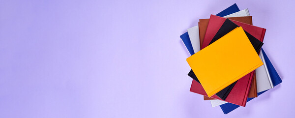 Stack of colorful books on purple background