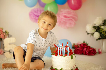 Obraz na płótnie Canvas Cute child, preschool boy, celebrating birthday at home with homemade cake with raspberries, mint and candies