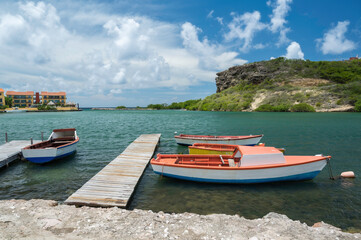 Small, colourful rowing boats, moored alongside a wooden jetty, on the Caribbean island of Curacao,...