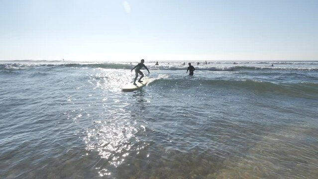 Girl surfing on a yellow surfboard with surf coach