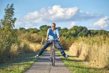 Fototapeta na wymiar lachender Senior mit Spaß auf dem Fahrrad