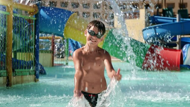 Cheerful boy child aqua park water slide splash at swimming pool happy childhood positive emotion