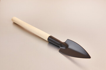 A small metal shovel with a wooden handle on a gray background.