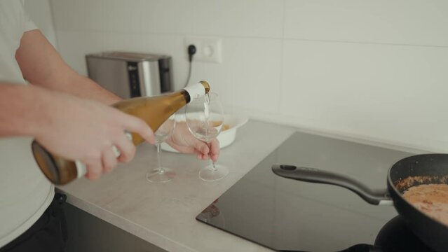 Zeitlupenaufnahme von einem Mann, der Wein in zwei Gl&auml;ser beim kochen sch&uuml;ttet