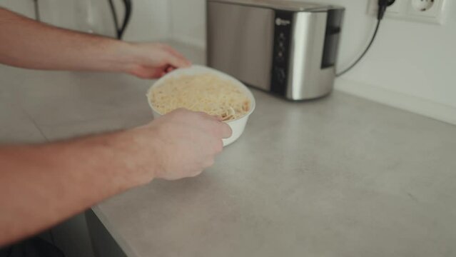 Zeitlupenaufnahme von einem jungen Mann, der einen Auflauf in den Backofen schiebt 