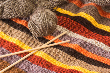 Tejido de lana de colores junto a un ovillo y unas agujas de madera de bambú. Vista superior y de cerca - obrazy, fototapety, plakaty