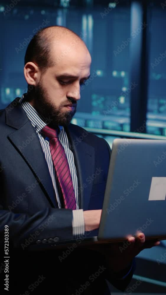Poster vertical video: it server engineer inspecting working computer processor with laptop, standing in pr